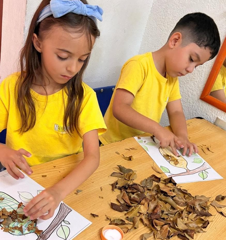 Niños pegando hojas secas en una manualidad